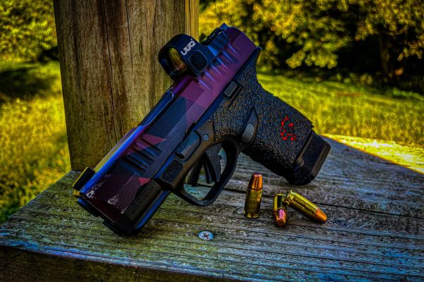 Showcasing a handgun equipped with a UUQ R26 RMS/RMSc Red Dot Sight placed on a wooden surface with bullets beside it.